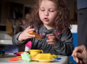Little girl playing with toy food. In the midst of many Childhood Development Myths, Educators agree kids need social and sensorial stimuli.